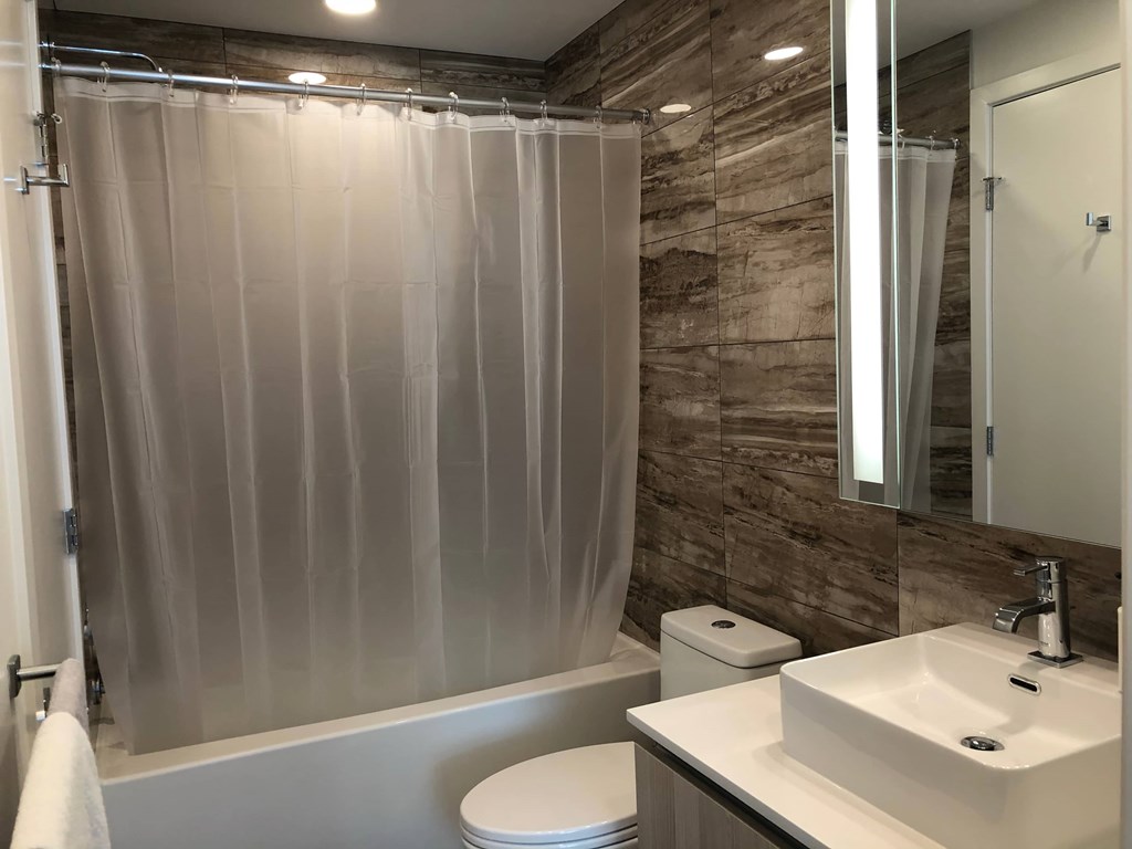 A bathroom with a toilet, sink, and shower curtain.