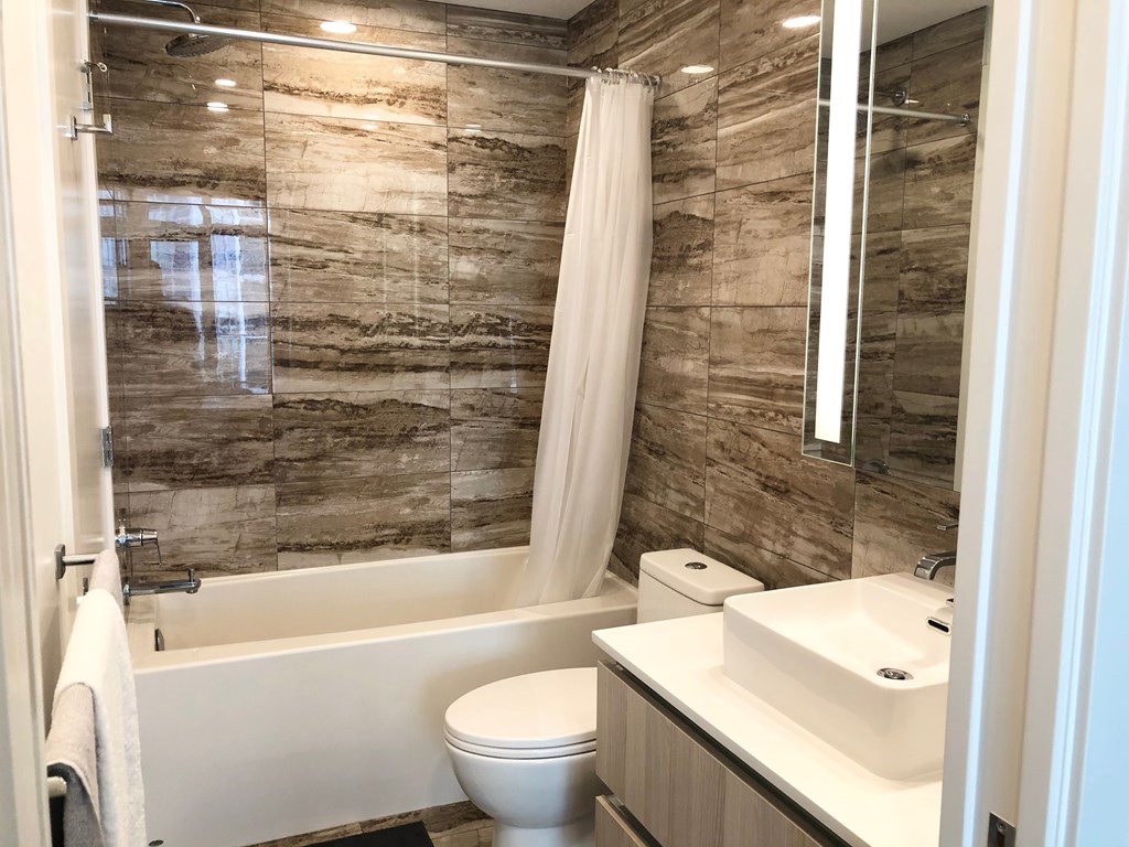 A bathroom with a white toilet, a white sink, and a shower with a white curtain.