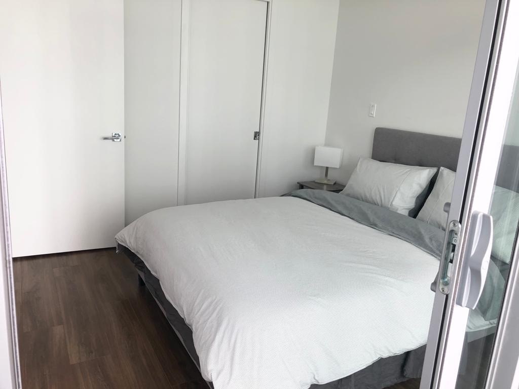 A white bed with a grey headboard and a white bedspread with two white pillows.