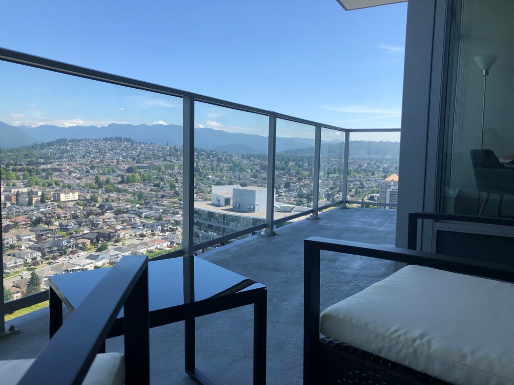 A balcony with a table and chairs overlooking a cityscape.