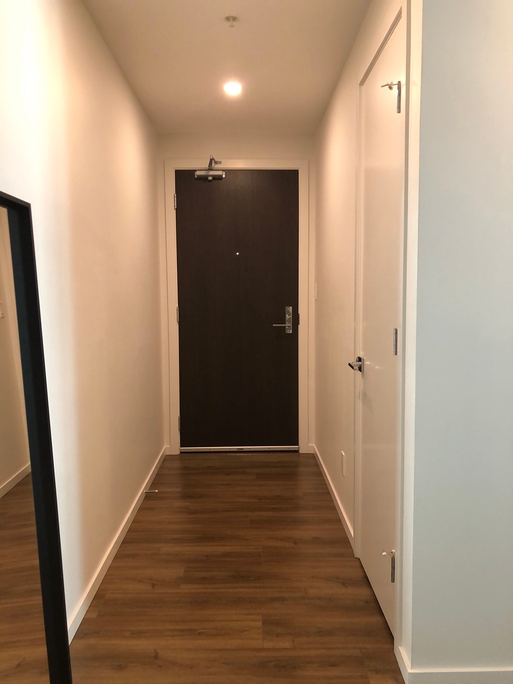 A long hallway with a black door at the end.