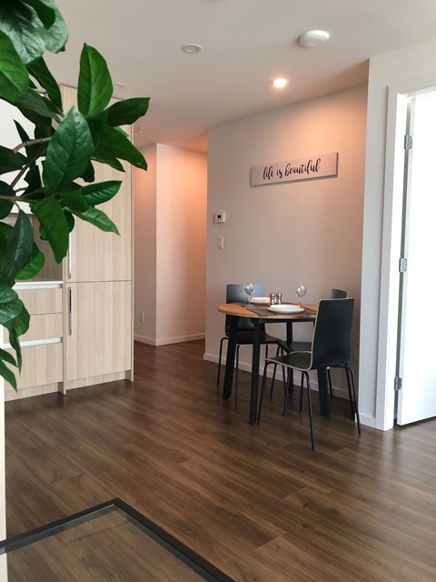 A dining room with a table set for two and a plant in the corner.