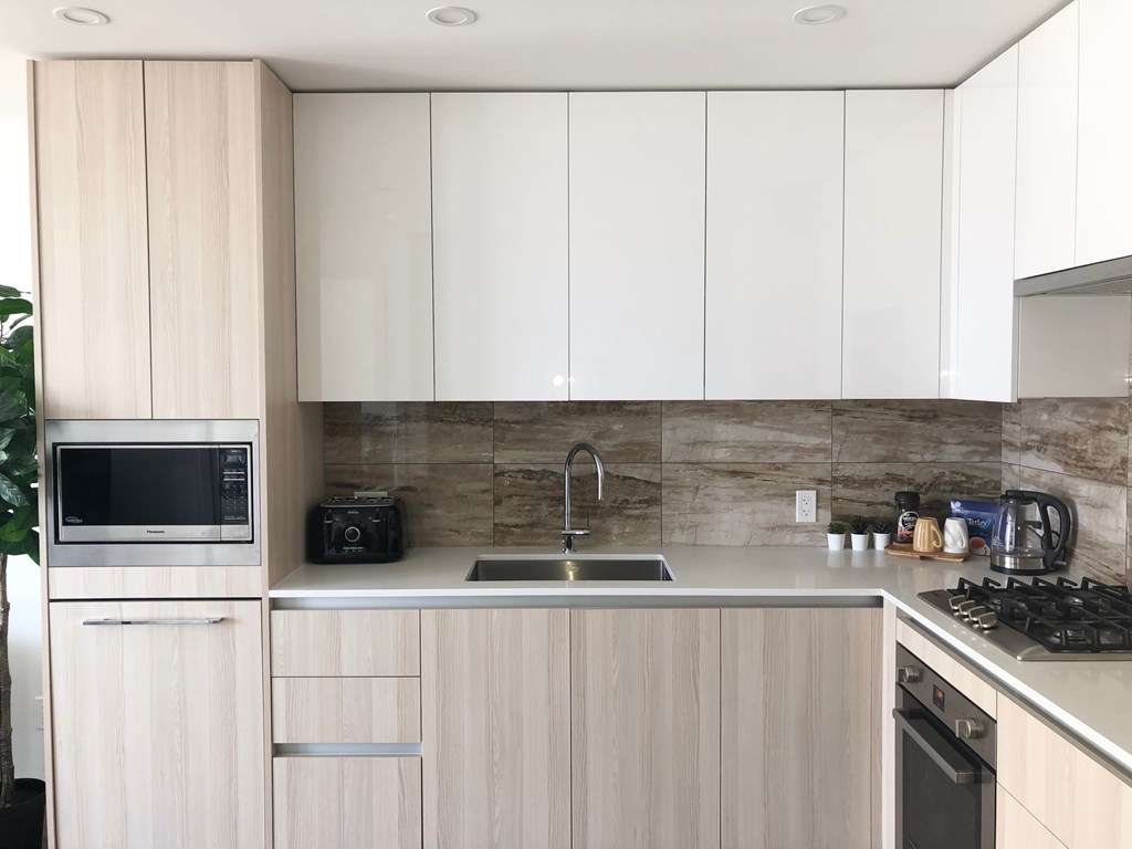 A kitchen with a sink, stove, and cabinets.