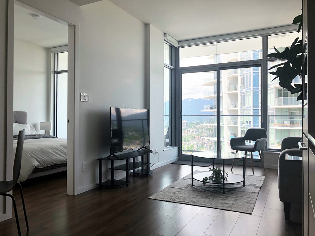 A living room with a television and a bed in the background.