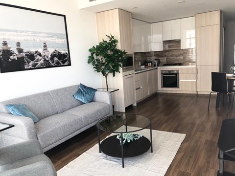 A living room with a grey couch and a glass table.