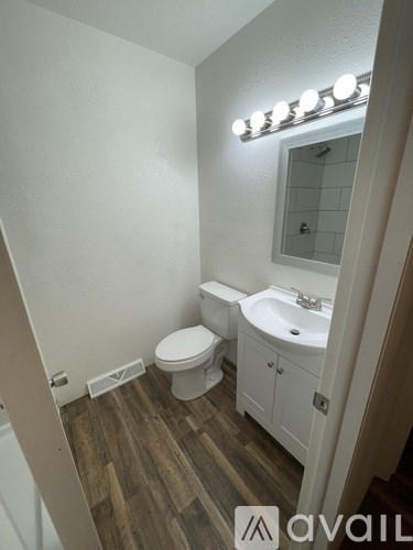 A bathroom with a toilet, sink, and mirror.