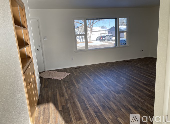 A room with wooden flooring and a window showing a snowy landscape outside.