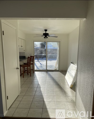 A room with a ceiling fan and a sliding glass door leading to a backyard.