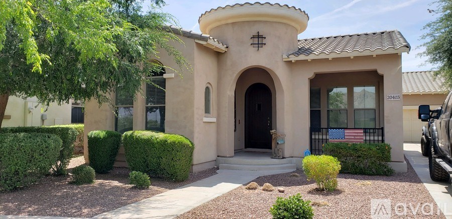 A house with a flag on the window has a small front yard.