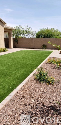 A backyard with a well-manicured lawn and a border of shrubs and flowers.