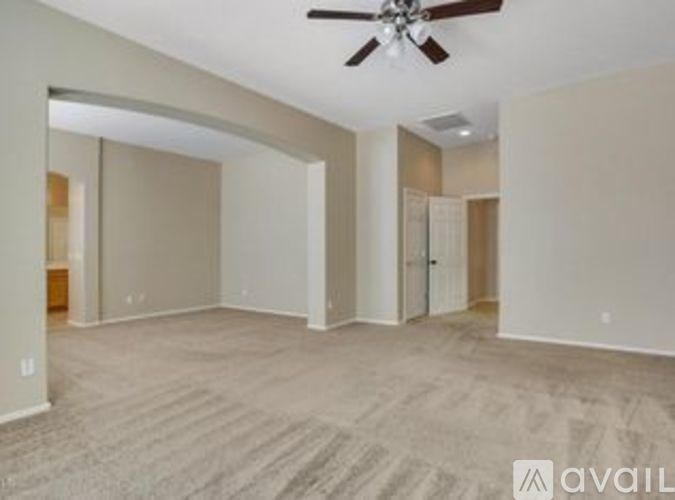 A spacious room with a ceiling fan and carpeted floor.