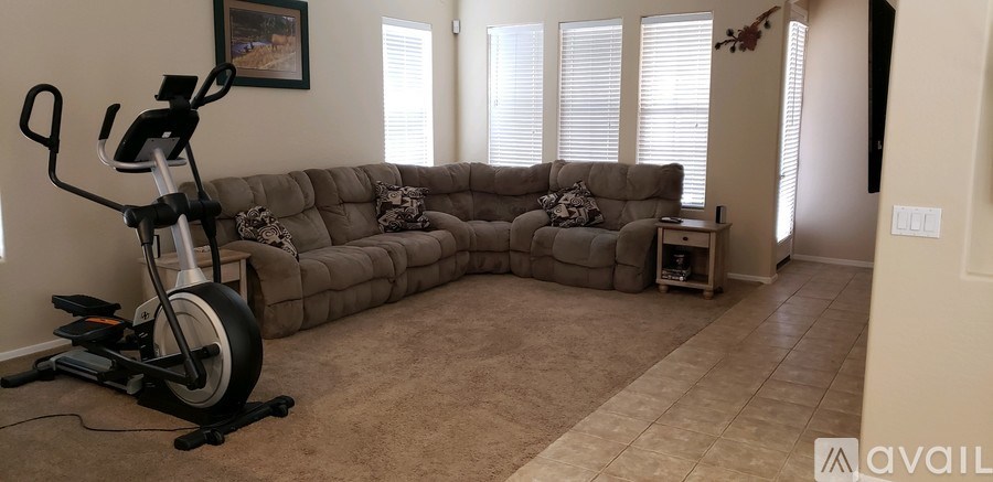 A room with a couch, a bike, and a window.