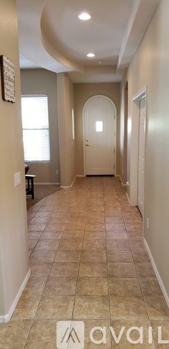 A long hallway with a tiled floor and a door at the end.