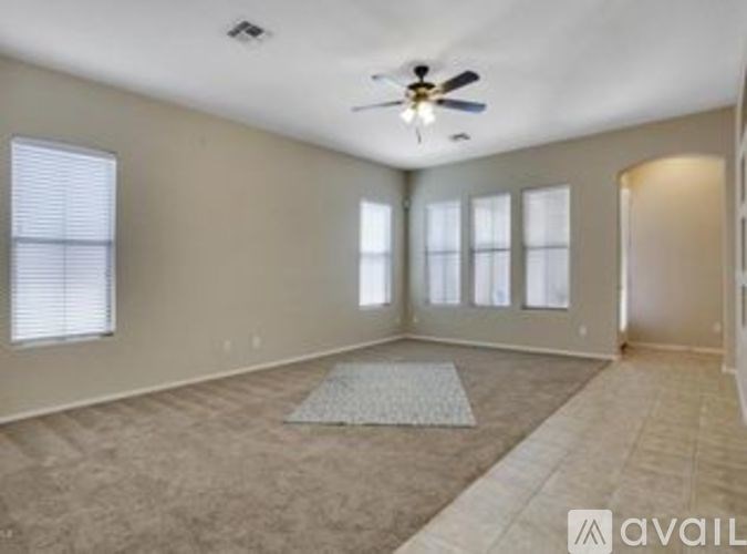 A spacious room with a ceiling fan and large windows.