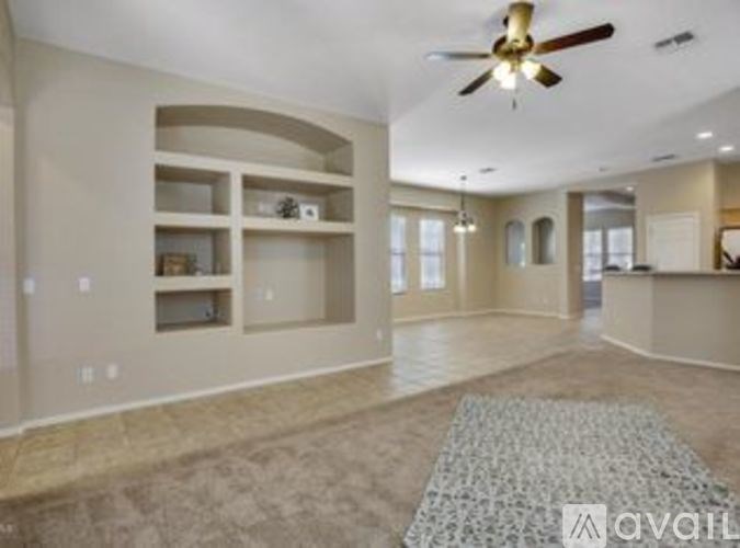 A spacious living room with a ceiling fan and built-in shelves.