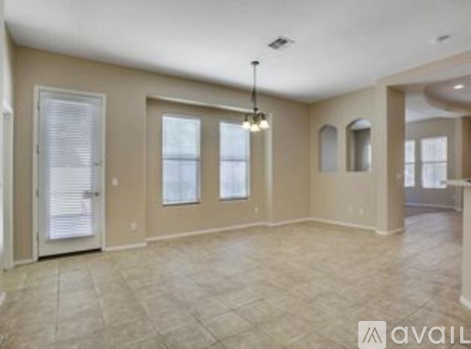 A spacious room with a tiled floor and a chandelier hanging from the ceiling.