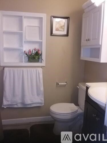 A bathroom with a toilet, sink, and a picture on the wall.