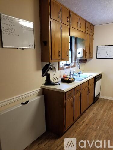 A kitchen with wooden cabinets and a whiteboard on the wall.