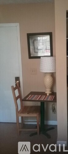 A small table with a chair and a picture on the wall.