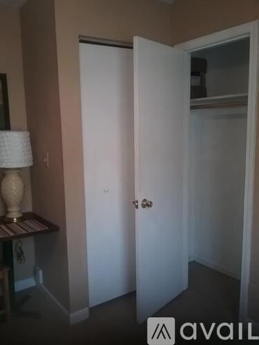 A white door is open in a room with a lamp on a table.