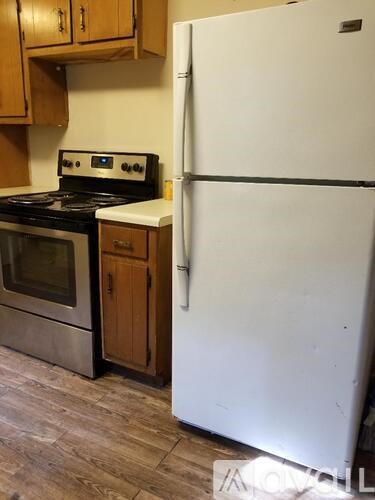 A white refrigerator stands next to a stove in a kitchen.