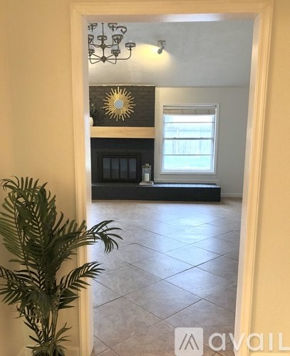 A room with a fireplace and a plant in the foreground.