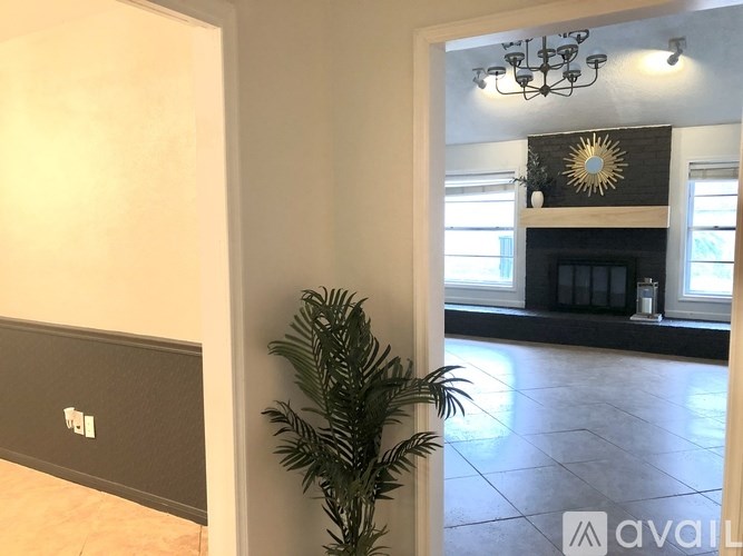 A room with a plant, a fireplace, and a chandelier.