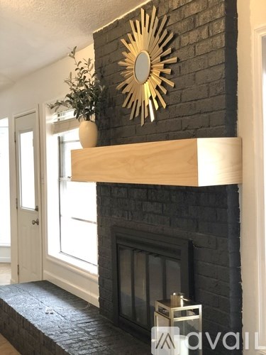 A fireplace with a mirror above it and a plant to the side.