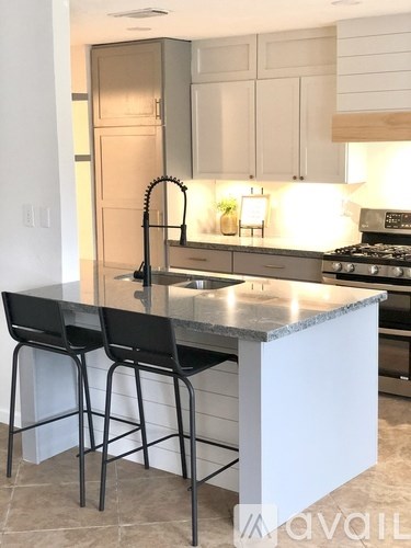 A kitchen with a black countertop and bar stools.