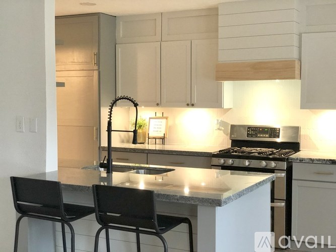 A modern kitchen with a granite countertop and black chairs.