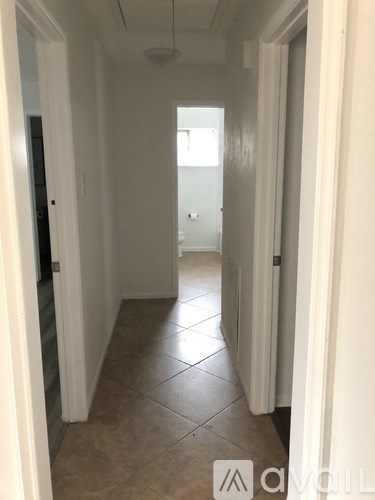 A hallway with tiled floors and white walls.