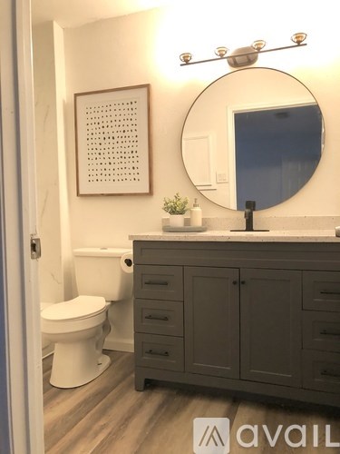 A bathroom with a toilet, sink, and a mirror.