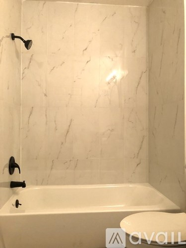 A white bathroom with a marble wall and a bathtub.