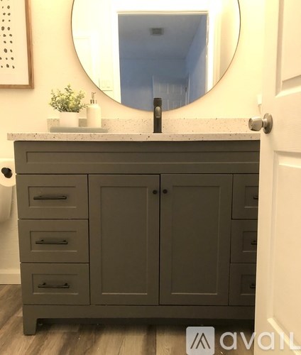A bathroom vanity with a round mirror above it.