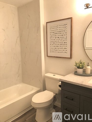 A bathroom with a toilet, tub, and a picture on the wall.