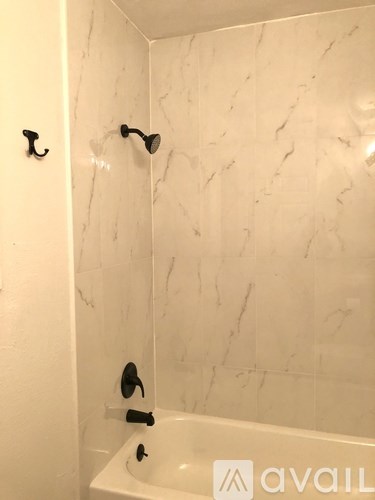 A white bathroom with a marble wall and a white bathtub.