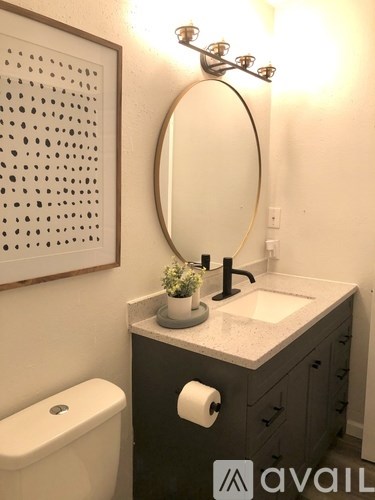 A bathroom with a toilet, sink, mirror, and a wall hanging.