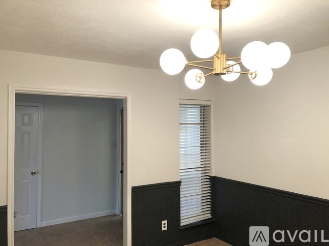 A room with a chandelier and a window with blinds.