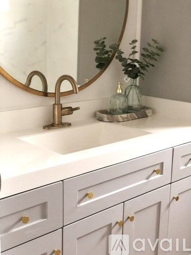 A bathroom with a marble countertop and a round mirror.