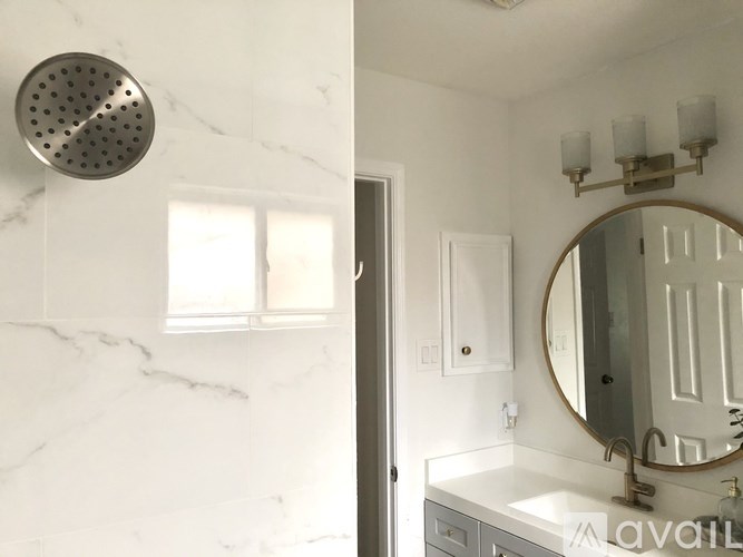 A bathroom with a marble wall and a round mirror.