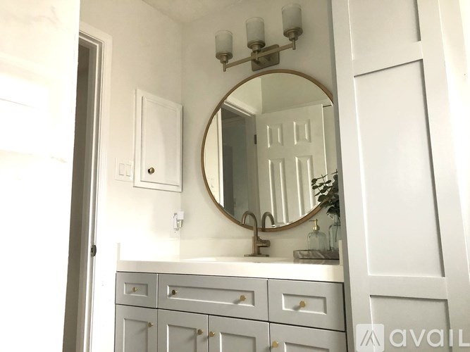 A bathroom with a mirror, light fixture, and sink.