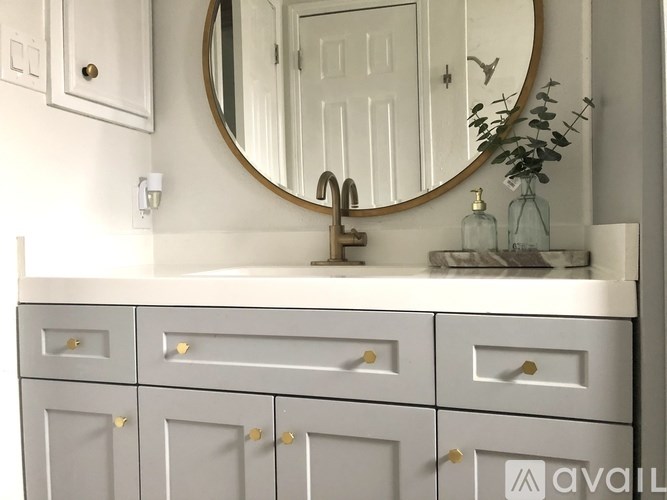 A bathroom vanity with a round mirror and a plant on top.
