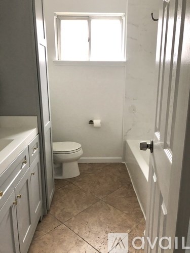 A bathroom with a toilet, sink, and a window.