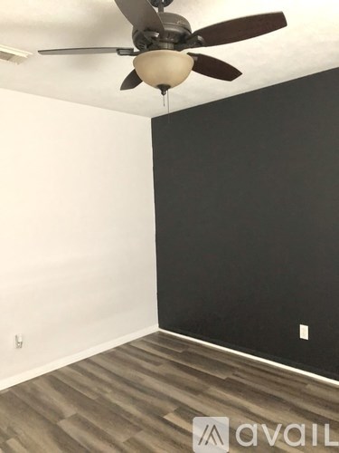 A room with a ceiling fan and wooden flooring.