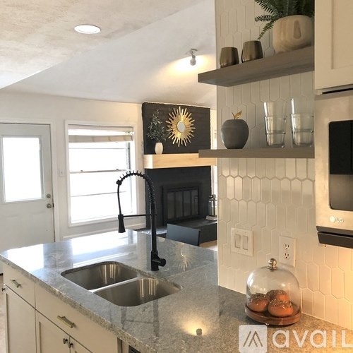 A kitchen with a granite countertop and a stainless steel sink.
