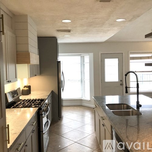 A kitchen with a stove, sink, and refrigerator.
