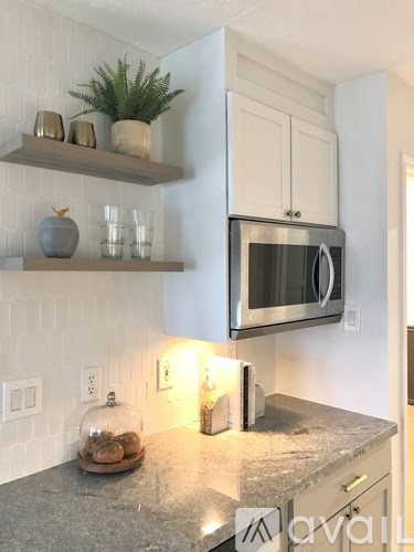 A kitchen with a granite countertop and a stainless steel microwave.