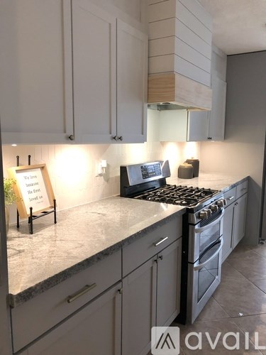 A kitchen with a stove, cabinets, and a sign on the counter.