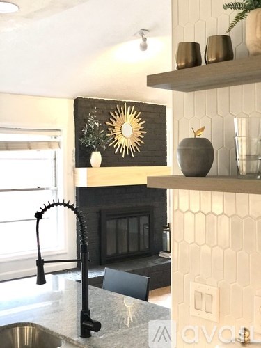 A kitchen with a black faucet and a black chair.