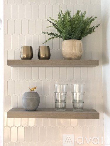 A shelf with a plant, vases, and cups on it.